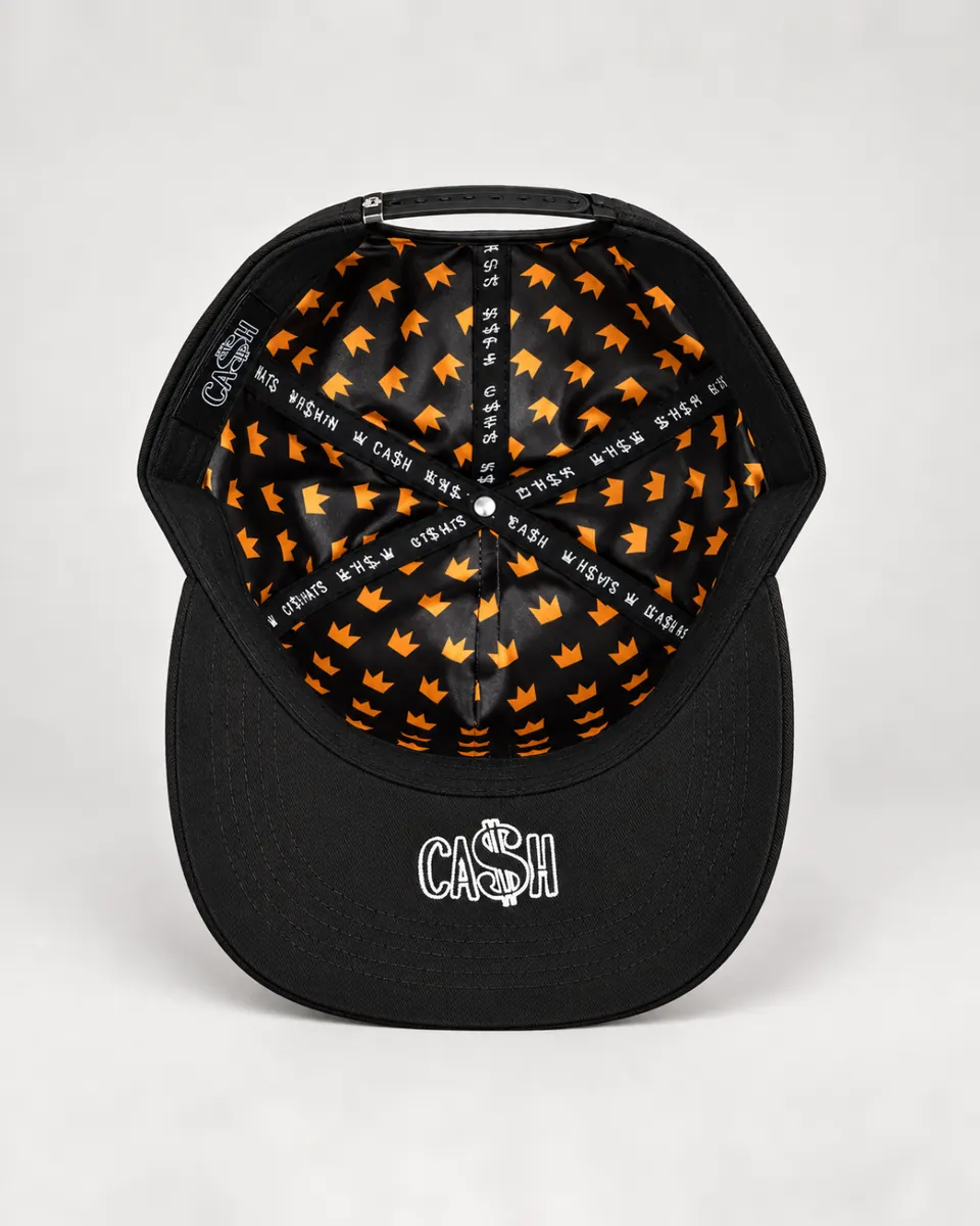 La gorra por dentro: forro con coronas naranjas, cintas con la palabra CA$H en las costuras y un CA$H blanco bajo la visera